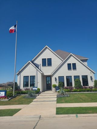 A modern white brick home with a lush landscape in Estates at Stacy Crossing by Normandy Homes (McKinney, TX).