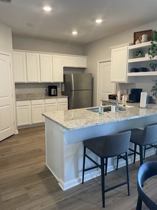 A modern kitchen featuring granite countertops, sleek white cabinets, and cozy seating at the breakfast bar.
