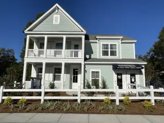 A charming pale green home with a welcoming porch and landscaped yard in Founders Corner by D.R. Horton (Lincolnville, SC).