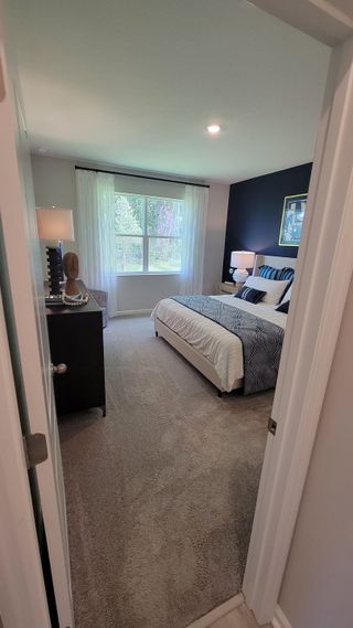 Cozy bedroom with plush carpet, a large window, and dark accent wall, featuring a stylish bed and elegant decor.