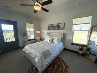 A cozy bedroom featuring a plush white bed, modern decor, and abundant natural light from large windows.