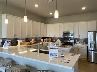 A modern kitchen with sleek white cabinets, stainless steel appliances, and a spacious island with elegant pendant lighting.