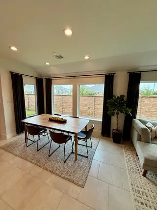 Model Home A bright dining area with a wooden table, modern chairs, and large windows offering outdoor views.