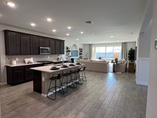 Model Home A spacious open-concept kitchen with a sleek island, dark cabinets, and a cozy living area with ample natural light.