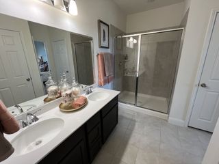 A modern bathroom with double sinks, elegant decor, a spacious glass shower, and sleek lighting.