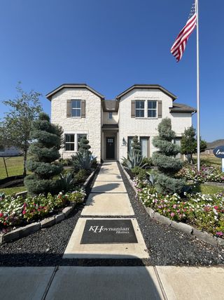 Model Home A beautiful two-story white brick home with lush landscaping in Marvida by K. Hovnanian® Homes, Cypress, TX.
