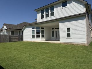 A modern white home with a spacious backyard in Blackhawk by Chesmar Homes (Pflugerville, TX).