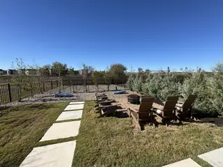 Street view A serene backyard with Adirondack chairs, fire pit, and pathway in Avery Centre by Landsea Homes (Round Rock, TX).