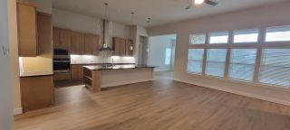 Model Home A spacious kitchen with sleek wooden cabinetry, a large island, and ample natural light from expansive windows.