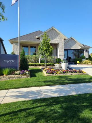 Charming brick home with lush landscaping at Painted Tree by Tri Pointe Homes (McKinney, TX).