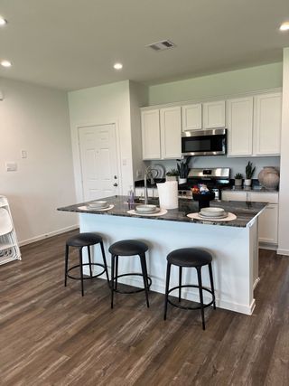 A modern kitchen with sleek white cabinetry, stainless steel appliances, and a central island with stylish stools.