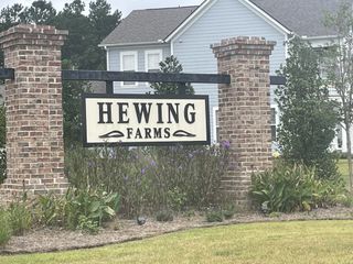 Street view A welcoming entrance with a brick sign and lush landscaping at Hewing Farms by Mungo Homes in Summerville, SC.