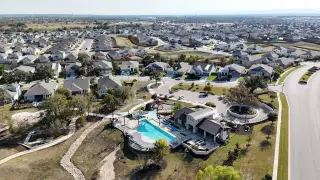 A stunning aerial view of the MorningStar community by Meritage Homes featuring homes, streets, and a community pool(Georgetown, TX).
