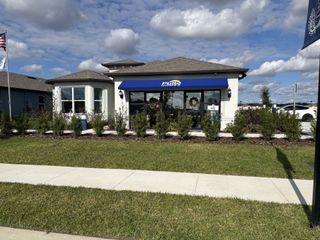 A charming, modern home with a blue awning and landscaped yard in Twisted Oaks by Pulte Homes (Wildwood, FL).