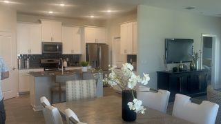 A modern kitchen and dining area featuring sleek cabinets, stainless appliances, and a stylish floral arrangement.