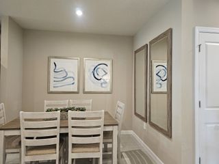 Model Home A cozy dining area featuring a wooden table, contemporary art, and elegant mirrors on neutral walls.