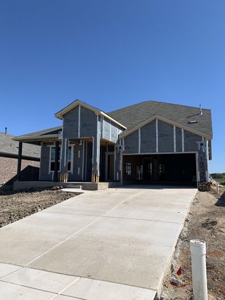 Street view A modern home under construction with a spacious driveway in Lagos by Pulte Homes (Manor, TX).