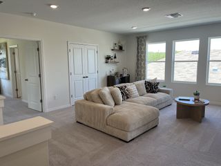 A cozy living area with plush sectional, soft beige carpet, and large windows for natural light. Modern and inviting space.