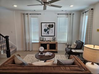 A cozy living room featuring a brown sofa, elegant decor, warm lighting, and a modern ceiling fan.