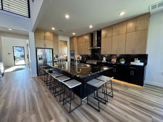 A modern kitchen with sleek black countertops, wood cabinetry, and an inviting island with bar seating.