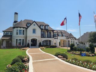 Model Home A grand stone and stucco home with manicured lawns in Kings Crossing by Grand Homes (Parker, TX).