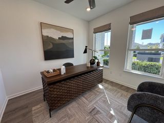 A dedicated workspace with large windows, bringing in natural light. The desk features a stylish textured front panel, adding a modern design element.