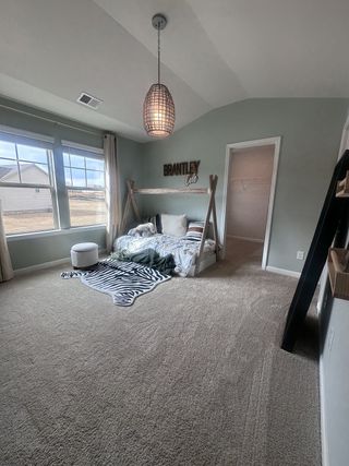 Model Home A charming kids' bedroom with a rustic wood-frame bed, soft carpet, and natural light from large windows in Dacula, GA.