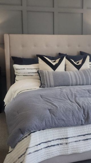 Model Home A luxurious bedroom with a statement accent wall, tufted headboard, and serene blue-gray hues.