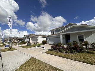 A close-up of one of the model homes, which is a two-story house with gray siding and a covered porch.