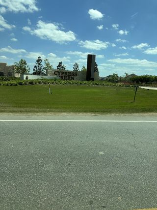 Street view Welcome to Cypress Green by Brightland Homes, featuring lush landscapes under a vibrant sky in Hockley, TX.