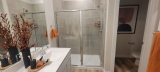 A sleek bathroom featuring a glass-enclosed shower, elegant fixtures, and warm orange accents for a modern touch.