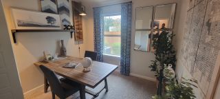 A cozy flex space in a Remington Ranch home, featuring a wooden table, decorative mirrors, and a window with natural light (San Antonio, TX).