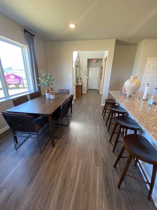 Model Home A chic dining area with wooden floors, a sleek table, and a granite-topped bar with stools, offering a cozy atmosphere.