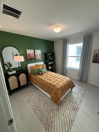 Model Home A cozy bedroom with a green accent wall, warm bedding, and tasteful décor.