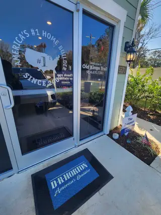 Street view Welcoming entry to Old Kings Trail by D.R. Horton, featuring a glass door and charming outdoor lighting in Jacksonville, FL.