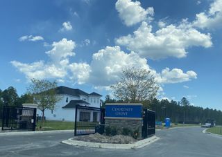 A modern gated entrance at Courtney Grove at SilverLeaf by ICI Homes in St. Augustine, FL, under a bright blue sky.