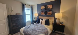 A cozy bedroom with deep blue accents, elegant wood art, and soft lighting for a serene ambiance.