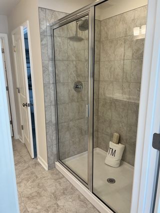 A sleek glass-enclosed shower with large tiled walls, exuding modern elegance and functionality.