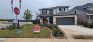A charming stone-accented home with a landscaped yard in Hunters Ranch by First America Homes (San Antonio, TX).