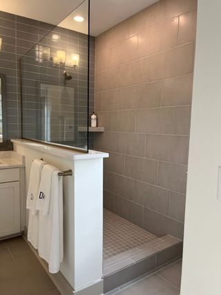 A modern shower with sleek gray tiles, glass enclosure, and elegant lighting, creating a relaxing spa-like atmosphere.
