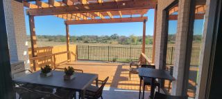 Model Home A charming patio with a wooden pergola, cozy seating, and serene views of the landscape.