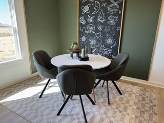 A cozy dining nook with a round table, four plush chairs, and a whimsical chalkboard wall art feature.