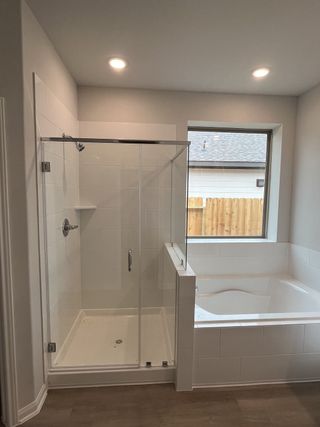 A modern bathroom with a glass-enclosed shower, soaking tub, and a bright window for natural light.