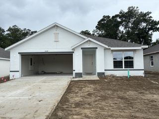 A modern white home with a spacious garage and simple landscaping in Autumn Glen by D.R. Horton (Belleview, FL).