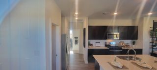 A modern kitchen with dark cabinetry, stainless steel appliances, and a spacious island with elegant lighting.
