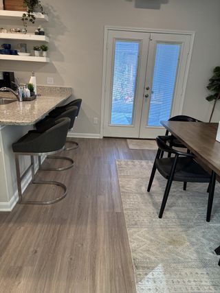 A cozy kitchen-dining area featuring sleek bar stools, granite countertops, and stylish open shelving.