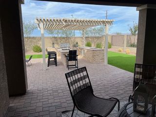 A cozy backyard patio with a modern pergola, outdoor dining area, and lush greenery. Ideal for entertaining and relaxation.