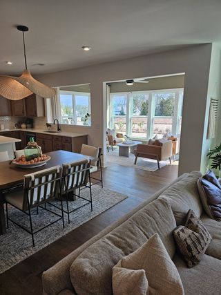 Model Home A modern, open-concept living area with natural light, wooden accents, and cozy seating overlooking a scenic view.