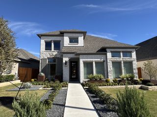 A modern white brick home with manicured landscaping in Lariat 60' by Perry Homes (Liberty Hill, TX).
