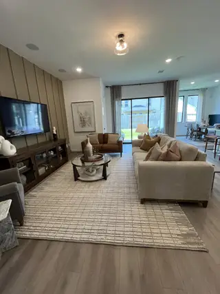 Model Home A cozy living room featuring plush sofas, a patterned rug, and large windows overlooking the backyard.